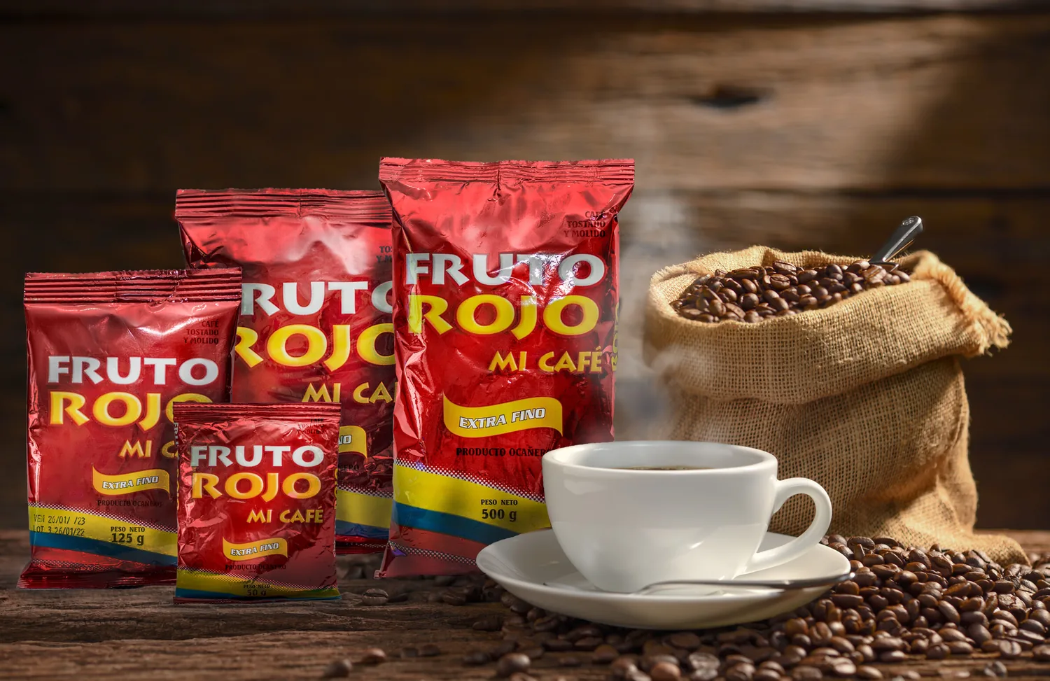 Bolsas de café Fruto Rojo Mi Café Extra Fino junto a un saco de grano y una taza